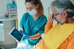 Dentist showing patient X-ray on tablet.